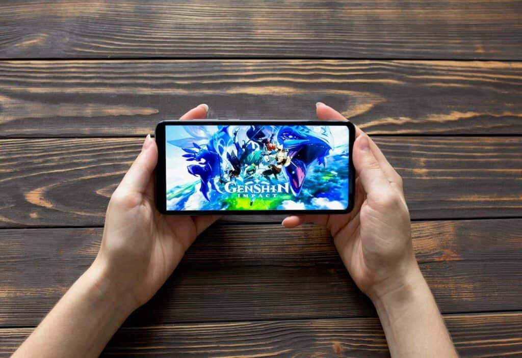 Person, die Genshin Impact auf einem Telefon spielt