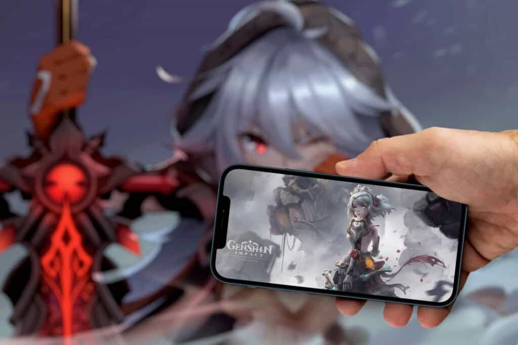 Mann, der ein Telefon mit Genshin Impact-Spiel hält