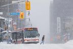 Ein Fußgänger überquert die Straße, während ein Stadtbus am Montag, den 17. Januar 2022, während eines Wintersturms in Toronto feststeckt. 