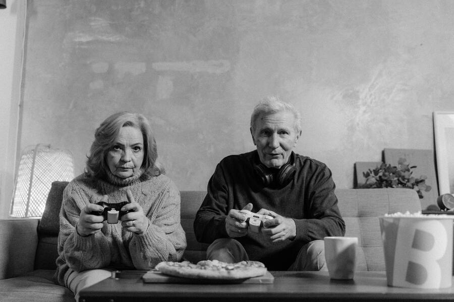 Graustufenfoto eines älteren Mannes und einer älteren Frau, die Videospiele spielen